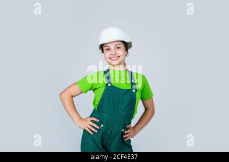 Assistent. Portrait von kleinen Mädchen mit Hut. Kleines Mädchen in Hut spielen in der Werkstatt. Kinderschutz und Sicherheit. Kleine lächelnde Baumeister im Helm. Glückliche Kindheit. Karriere Anleitung Idee. Stockfoto