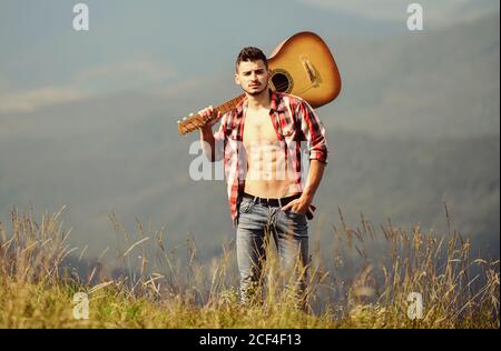 Mann mit Gitarre auf dem Gipfel des Berges. Beste weg von Stadt zu entkommen. Guy Wanderer Natur pur genießen. Ausflüge in die Natur. Schönheit der Natur. Frische Luft der Berge. Ferienhäuser Reiseziele. Allein gehen. Stockfoto