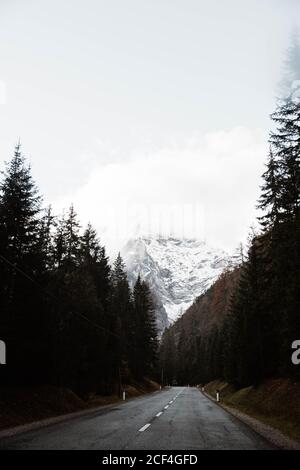 Leere Route zwischen holzigen Dolomiten und wolkenbewachsenen Himmel Stockfoto