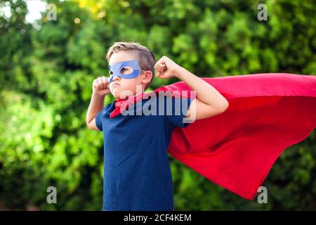 Superheld Kind Junge vor grünem Hintergrund im Freien. Kindheit, Erfolg und Machtkonzept Stockfoto