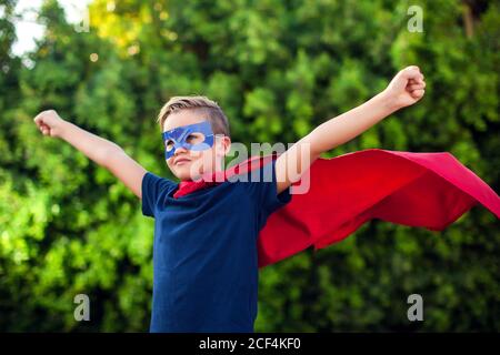 Superheld Kind Junge vor grünem Hintergrund im Freien. Kindheit, Erfolg und Machtkonzept Stockfoto