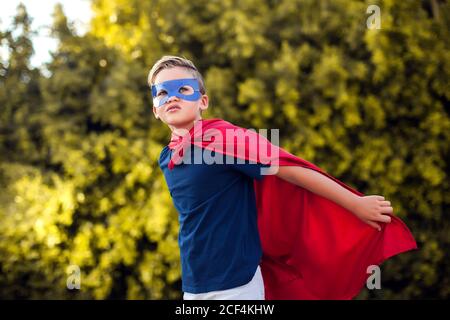 Superheld Kind Junge vor grünem Hintergrund im Freien. Kindheit, Erfolg und Machtkonzept Stockfoto