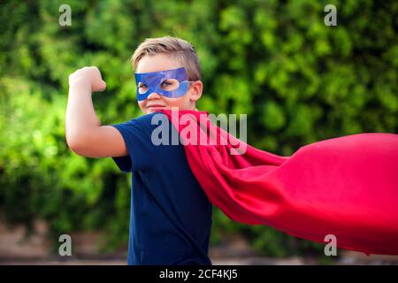 Superheld Kind Junge vor grünem Hintergrund im Freien. Kindheit, Erfolg und Machtkonzept Stockfoto