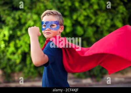 Superheld Kind Junge vor grünem Hintergrund im Freien. Kindheit, Erfolg und Machtkonzept Stockfoto