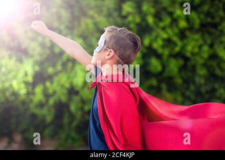 Superheld Kind Junge vor grünem Hintergrund im Freien. Kindheit, Erfolg und Machtkonzept Stockfoto