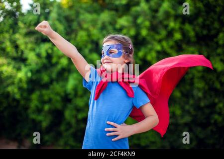 Superheld Kind Mädchen vor grünem Hintergrund im Freien. Kindheit, Erfolg und Machtkonzept Stockfoto