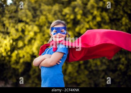 Superheld Kind Mädchen vor grünem Hintergrund im Freien. Kindheit, Erfolg und Machtkonzept Stockfoto