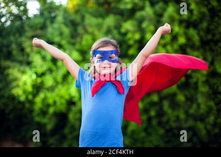 Superheld Kind Mädchen vor grünem Hintergrund im Freien. Kindheit, Erfolg und Machtkonzept Stockfoto