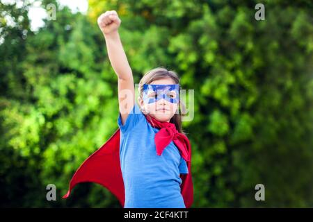 Superheld Kind Mädchen vor grünem Hintergrund im Freien. Kindheit, Erfolg und Machtkonzept Stockfoto