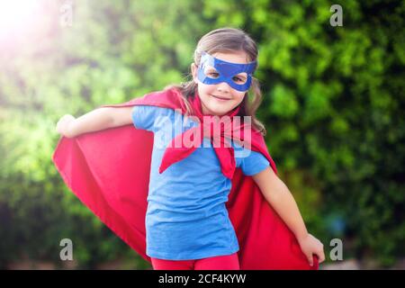 Superheld Kind Mädchen vor grünem Hintergrund im Freien. Kindheit, Erfolg und Machtkonzept Stockfoto