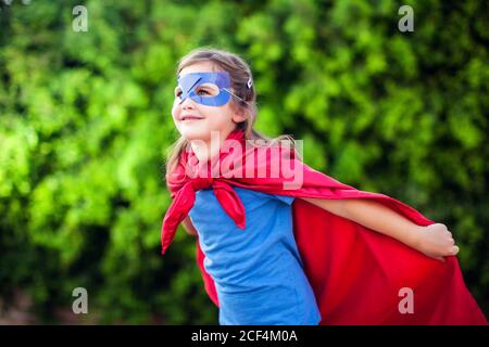 Superheld Kind Mädchen vor grünem Hintergrund im Freien. Kindheit, Erfolg und Machtkonzept Stockfoto