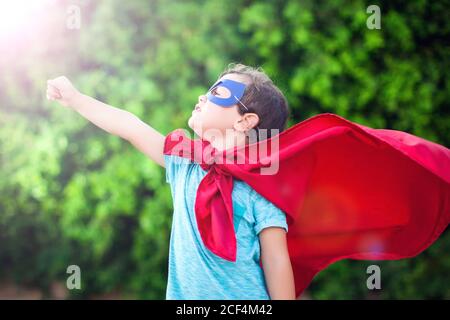 Superheld Kind Junge vor grünem Hintergrund im Freien. Kindheit, Erfolg und Machtkonzept Stockfoto