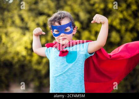 Superheld Kind Junge vor grünem Hintergrund im Freien. Kindheit, Erfolg und Machtkonzept Stockfoto