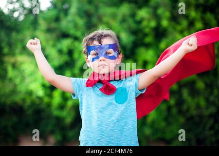 Superheld Kind Junge vor grünem Hintergrund im Freien. Kindheit, Erfolg und Machtkonzept Stockfoto