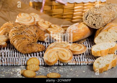 Sortiment an frischen Backwaren auf wicker Mat mit Korb auf hölzernen Hintergrund Stockfoto