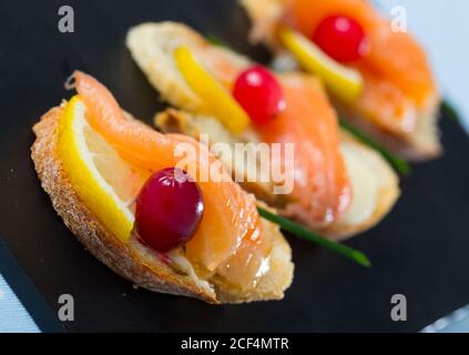 Leckere Sandwiches mit geräuchertem Lachs, Butter, Zitrone und Preiselbeeren Stockfoto