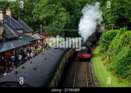 Familien warten im Lake District auf einem Bahnsteig, als die Dampflok Repulse die Waggons/Waggons in Cumbria, England, passiert Stockfoto