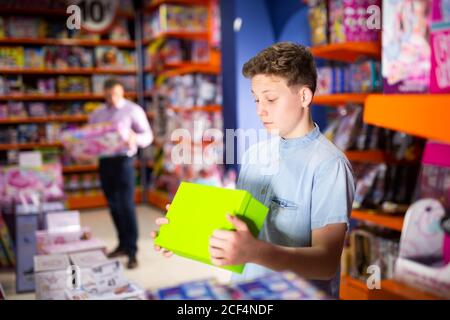 Fokussierter Teenager Auswahl neuer Spielzeuge in modernen Spielwarenladen Stockfoto