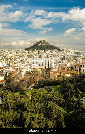 Apartmentgebäude in der Nähe von grünen Berggipfel an bewölkten Tag in Athen, Griechenland Stockfoto