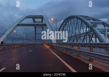 Autos fahren am späten Abend unter den Bögen der Krimbrücke. Die LEDs leuchten. Langweilig Stockfoto