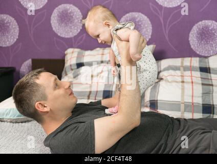 Ein 30-jähriger Mann spielt mit seiner kleinen Tochter. Das Baby blickt in die Augen des Papstes. Glück Eltern zu sein Stockfoto