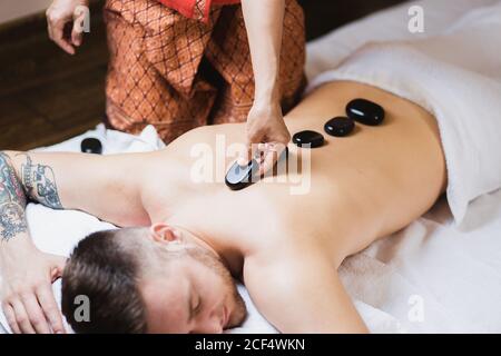 Mann in Wellness- und Spa-Umgebung mit einem heißen Stein Therapiesitzung Stockfoto