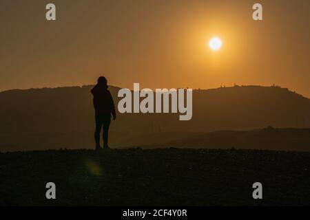 Silhouette des Touristen steht auf dem Feld in hellen Rücken beleuchtet von Sonnenuntergang Himmel, Italien Stockfoto