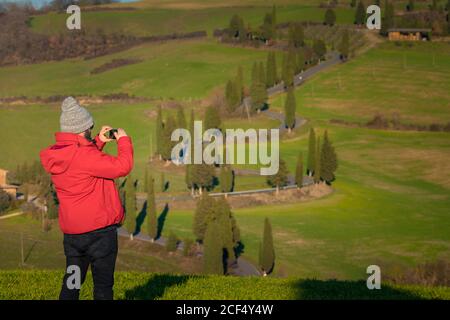 Rückansicht des Reisenden Mannes, der schöne grüne Landschaft in der Toskana, Italien fotografiert Stockfoto