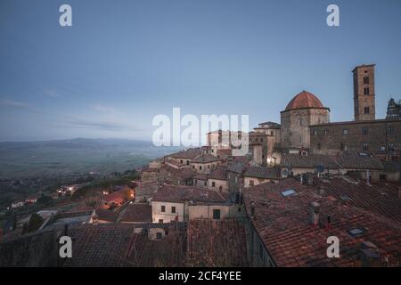Außenansicht der alten roten Backsteingebäude der Stadt Volterra gegen blauen Himmel, Italien Stockfoto