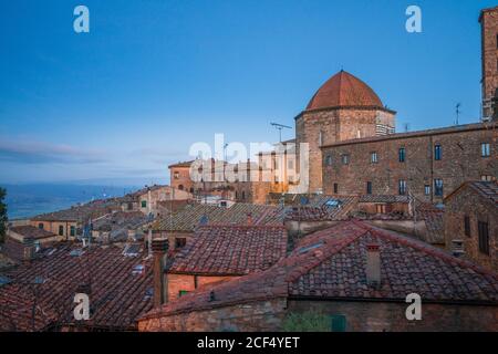 Außenansicht der alten roten Backsteingebäude der Stadt Volterra gegen blauen Himmel, Italien Stockfoto