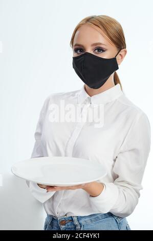 Porträt der Kellnerin in schwarzer Maske isoliert auf weißem Studio Hintergrund Stockfoto