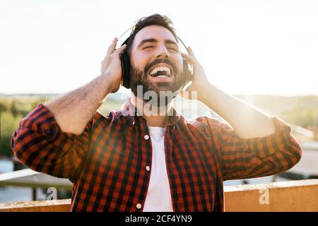 Ein Porträt eines jungen Mannes, während er draußen Musik hört. Er lächelt und ist glücklich Stockfoto