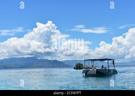 Zwei kleine Boote vor der Küste von South Sea Island. Die Berge von Viti Levu können über das blaue Wasser der Nadi Bay gesehen werden. Fidschi, Südpazifik. Stockfoto