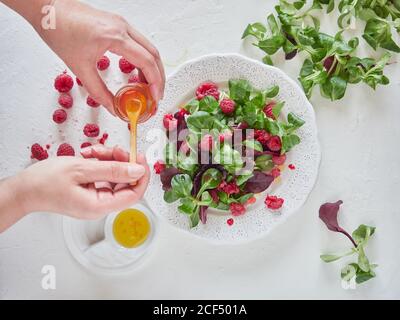 Person, die Himbeersaft in Obstsalat Stockfoto