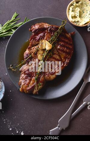 Gegartes Ribeye Black angus Prime Beef Steak mit Butter, Meersalz, Kräutern und Knoblauchscheiben. Stockfoto