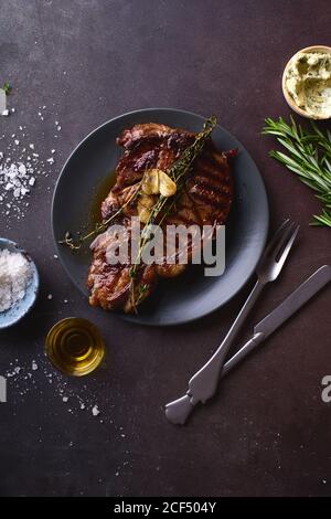 Gegartes Ribeye Black angus Prime Beef Steak mit Butter, Meersalz, Kräutern und Knoblauchscheiben. Stockfoto