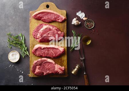 Draufsicht auf rohe schwarze angus Prime Beef Steaks auf Holzschneidebrett: Rib Eye, Chuck Roll, Striploin und Picanha. Stockfoto