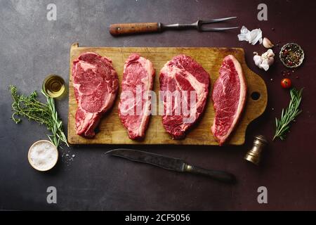 Draufsicht auf rohe schwarze angus Prime Beef Steaks auf Holzschneidebrett: Rib Eye, Chuck Roll, Striploin und Picanha. Stockfoto