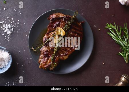 Gegartes Ribeye Black angus Prime Beef Steak mit Butter, Meersalz, Kräutern und Knoblauchscheiben. Stockfoto