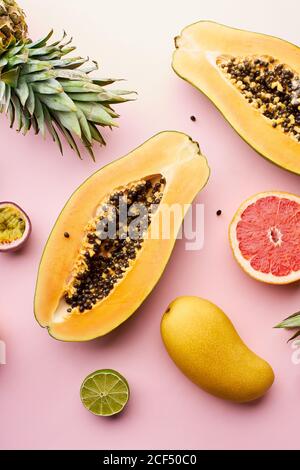 Draufsicht kreatives Layout mit exotischen Sommerfrüchten: Papaya, Ananas, Limette, gelbe Mango und Passionsfrucht auf rosa Hintergrund Stockfoto