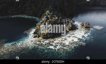 Luftaufnahme von rauen Felsen auf der Insel mit grünen Pflanzen zwischen blauen ruhigen Meer in Coron, Philippinen Stockfoto