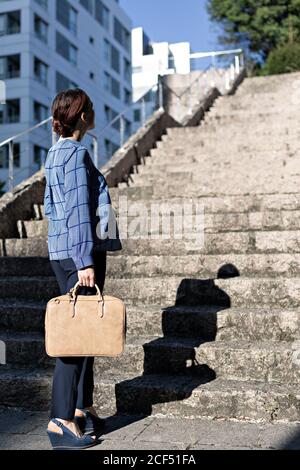 Niedriger Winkel der eleganten Unternehmer mit stilvollen Aktentasche zu Fuß nach oben Raue Schritte an sonnigen Tagen auf der Stadtstraße Stockfoto