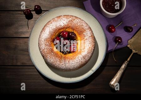 Runde Kirschtorte in der Platte auf hölzernen Tisch. Dunkle Essen Stockfoto