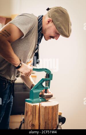 kaukasische Leder Handwerk Schnurrbart Mann trägt Tasse arbeiten als Handwerker In seiner Werkstatt Stockfoto