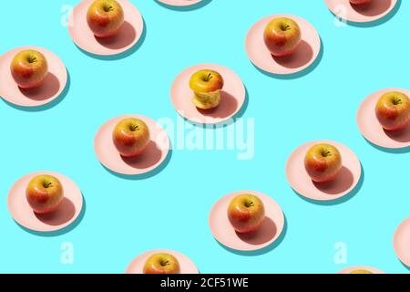 Frische Äpfel und Apfel in Teller auf cyanfarbenem Hintergrund gebissen. Lebhaft farbenfrohe Muster Stockfoto