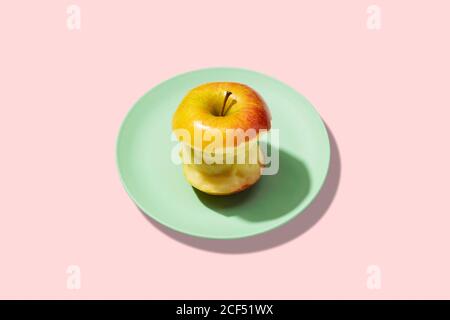 Frischer Apfel in Teller auf rosa Hintergrund. Lebhaft farbenfrohe Muster Stockfoto