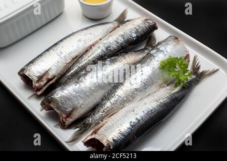 Frisch gewaschene und geschalkene Fische ohne Kopf auf weißem Teller Stockfoto