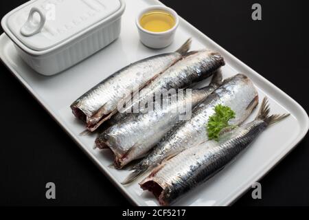 Frisch gewaschene und geschalkene Fische ohne Kopf auf weißem Teller Stockfoto