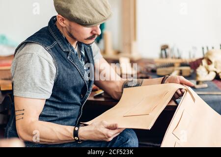 kaukasische Leder Handwerk Schnurrbart Mann trägt Tasse arbeiten als Handwerker In seiner Werkstatt Stockfoto