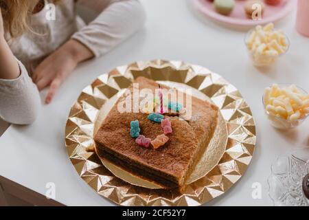Von oben Blick auf leckeren Geburtstagskuchen mit Kerze dekoriert Und Gelee Bonbons in Form von Nummer fünf auf Tisch im Zimmer Stockfoto
